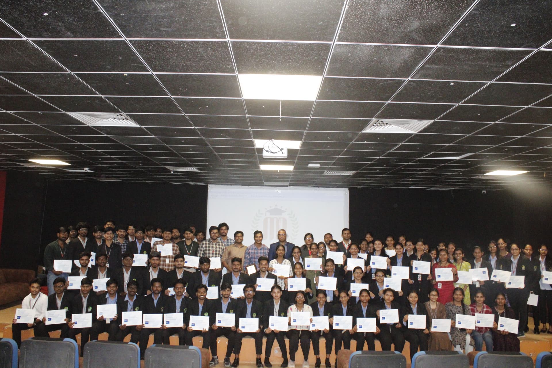 A group of event participants holding certificates in the auditorium