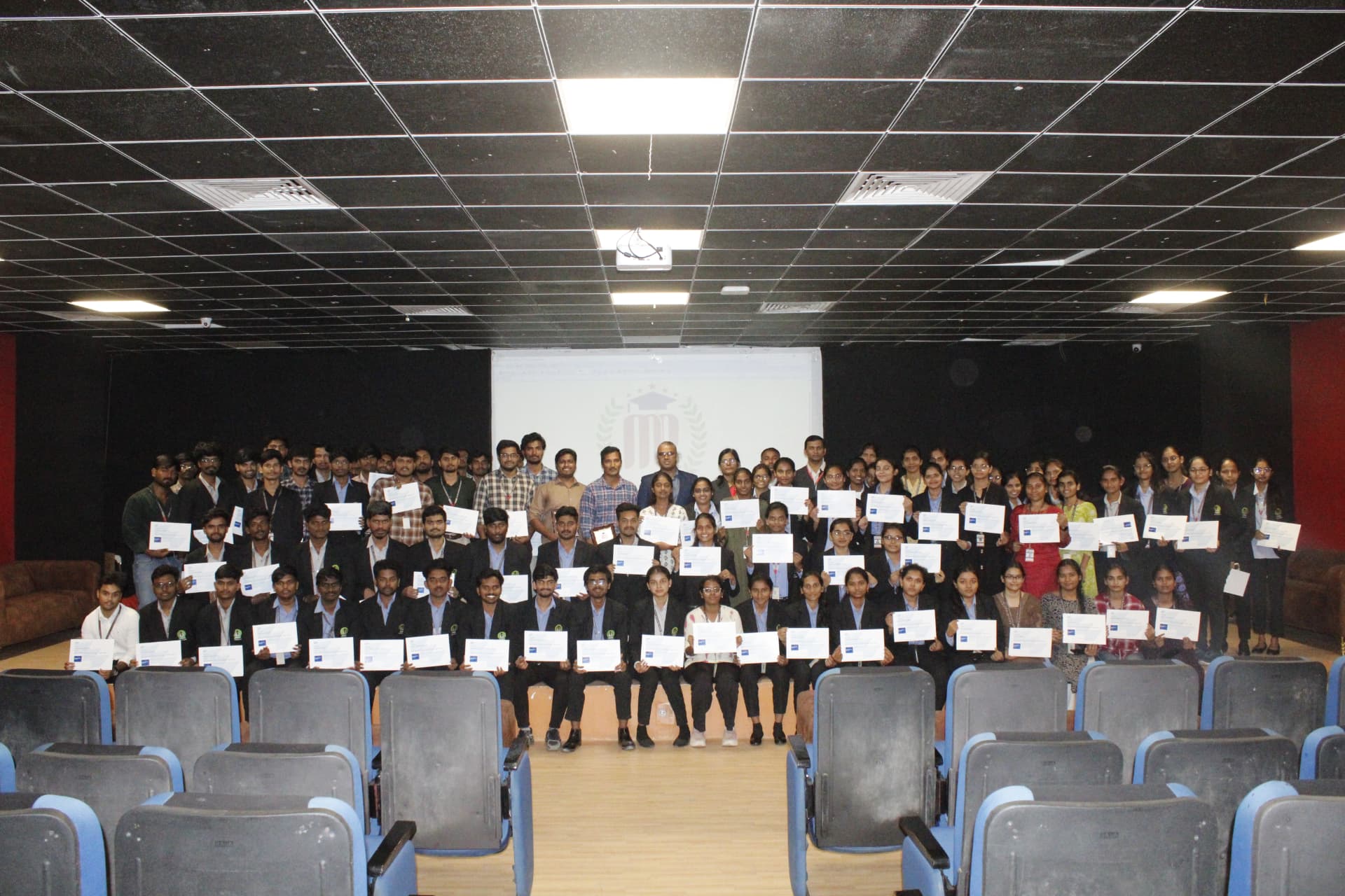 Event participants posing together with certificates in the auditorium
